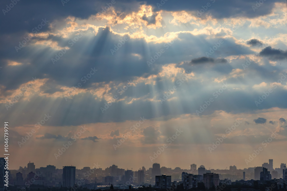 Early morning sun rays break through thick clouds over a sleeping city.