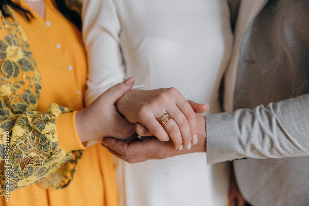 Obraz premium Parents hold their daughter's hand on their wedding day. A girl's wedding with the support of her parents. Golden wedding ring