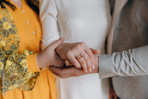 Parents hold their daughter's hand on their wedding day. A girl's wedding with the support of her parents. Golden wedding ring