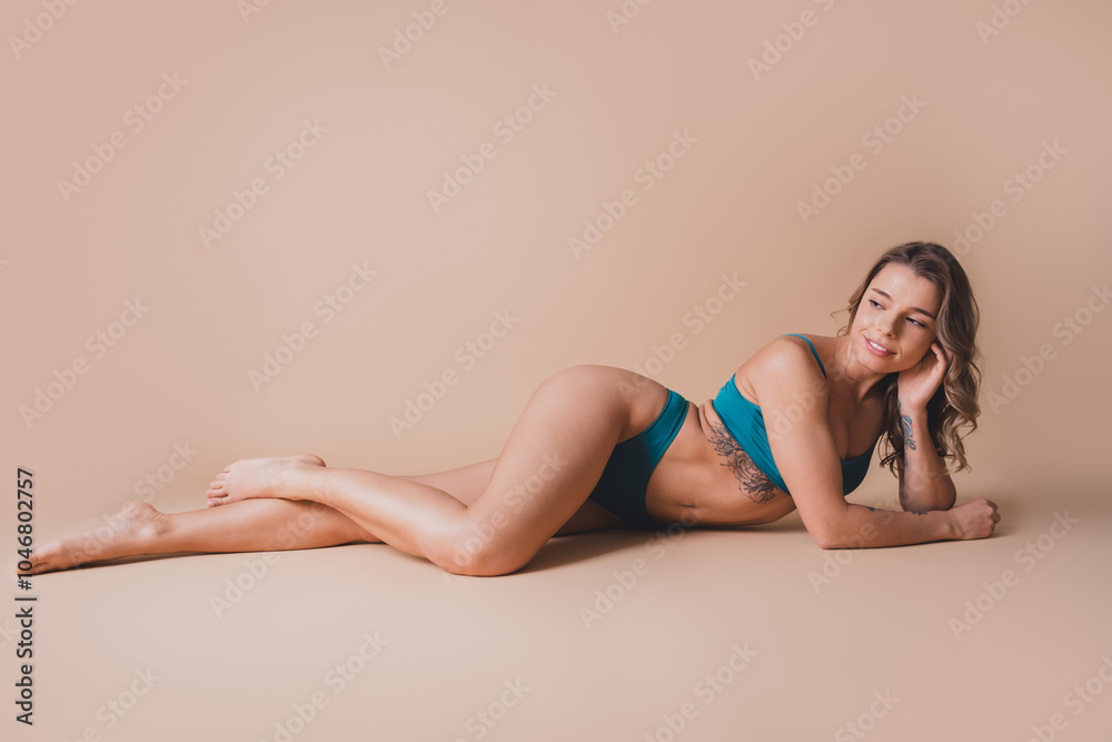 Obraz premium Full body photo of attractive young girl lying floor look empty space wear cyan fashion lingerie isolated beige background no filter