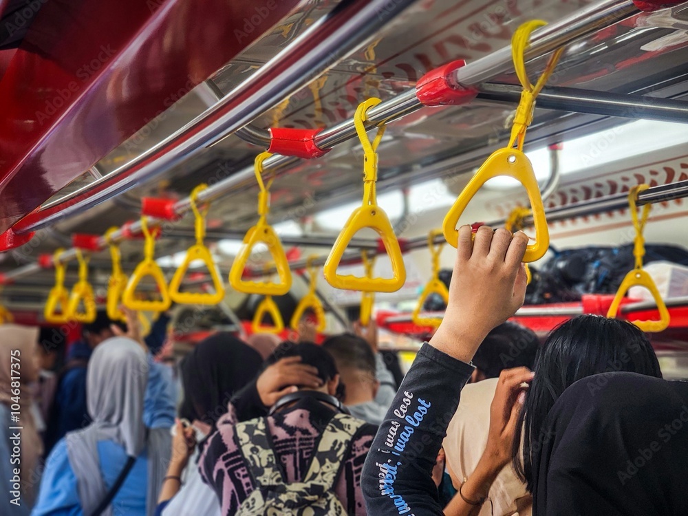 In the crowded train, a person was standing and holding a yellow handle hanging at the top of the train, the atmosphere of the trip during rush hour In the crowded train, a person was standing and holding a yellow handle hanging at the top of the train, the atmosphere of the trip during rush hour