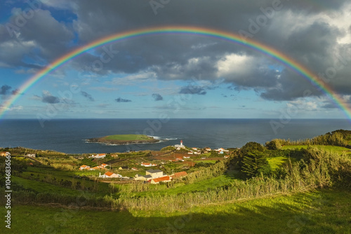 Breathtaking view of the amall village and lighthouse at São Jorge island in Azores with huge rainbow in the sky Portugal photo