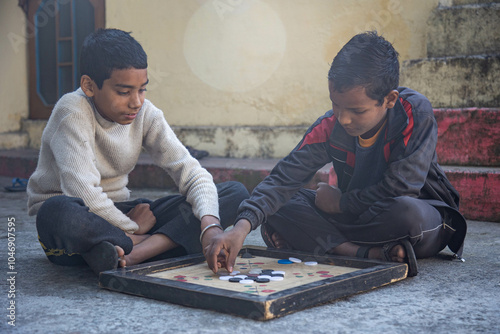 Indian village boys focus intently on a carrom board while playing together in a courtyard, surrounded by pastel-colored walls and a calming atmosphere. photo