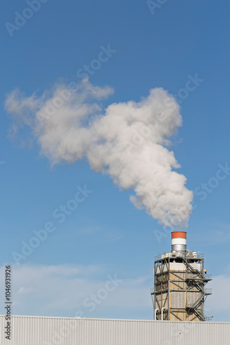 Industrial factory manufacturing plant chimney emitting steam and gas flue gases