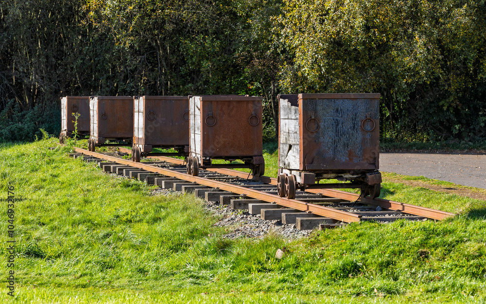 Rusty coal mine hutches or small wagons on narrow gauge rail tracks above ground Rusty coal mine hutches or small wagons on narrow gauge rail tracks above ground