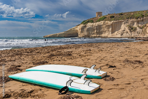 Surfboards on the sandy beach of Santa Caterina di Pittinuri. The watchtower can be seen at the top of the cliff. Sardinia, Italy. photo