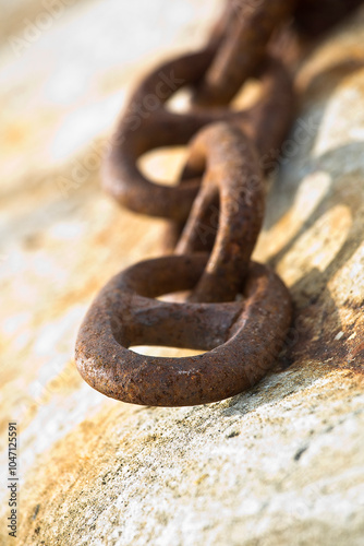 Detail of an old rusty metal chain anchored to a concrete block