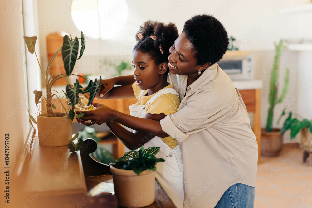 Mother teaching daughter the art of indoor plant care with a spray bottle Mother teaching daughter the art of indoor plant care with a spray bottle