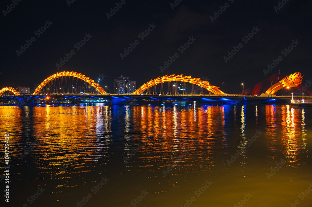 Obraz premium Dragon Bridge over the Han River is a famous landmark in the city of Da Nang in Vietnam at night with a golden backlight