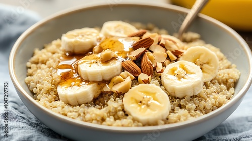 Delicious bowl of quinoa topped with sliced banana, honey, and almonds for a nutritious breakfast.