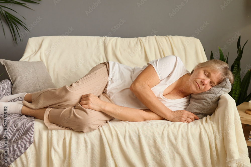 Peaceful older woman sleeping relaxing on comfortable couch with closed eyes calm lazy mature female enjoying free time on weekend resting in living room