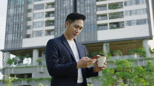 Happy Asian business man using phone and drink coffee on the street , tower