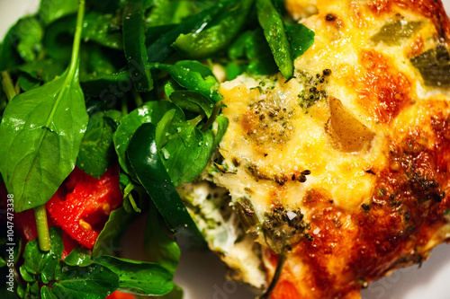 Closeup of a broccoli pie with spinach, eggs, cheese, tomatoes, onions, and other vegetables and herbs photo