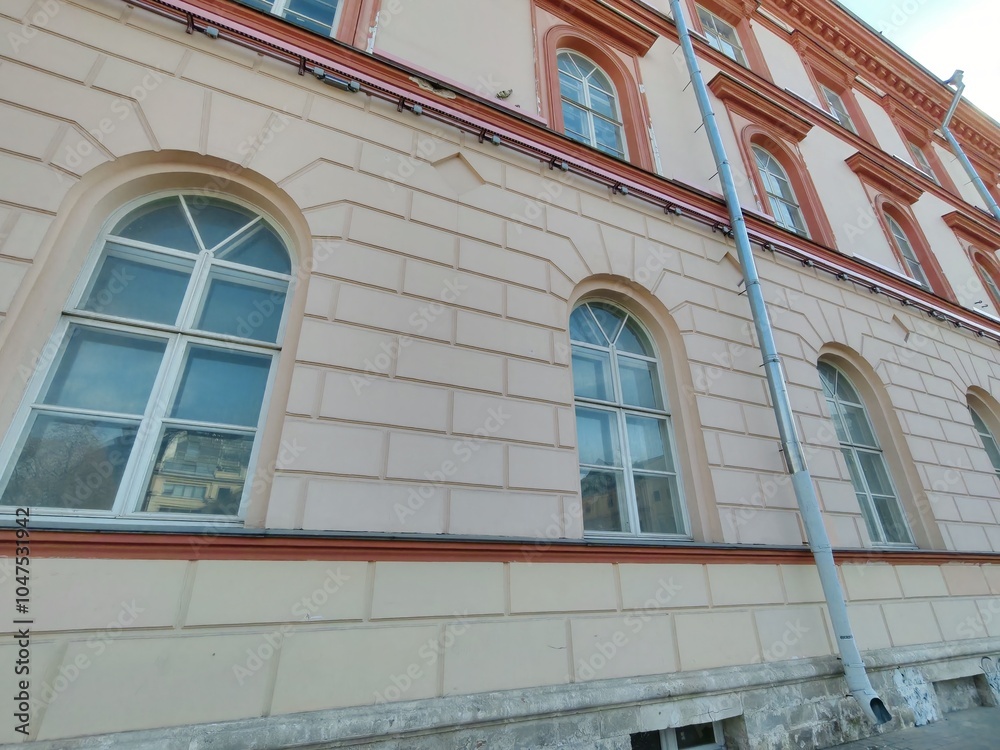 Naklejka premium two-story classical building with intricate architectural details, large windows, and a light blue facade. The structure highlights the importance of preserving historical buildings in modern urban