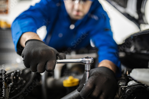 A mechanic working diligently on a car engine while using a ratchet tool in a well-lit workshop during the day
