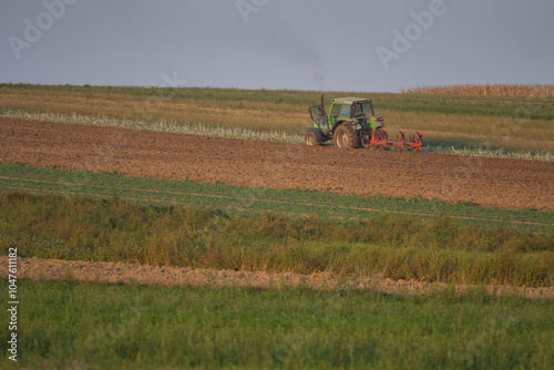 Agriculture machinery in action a tractor plows a field on a bright day