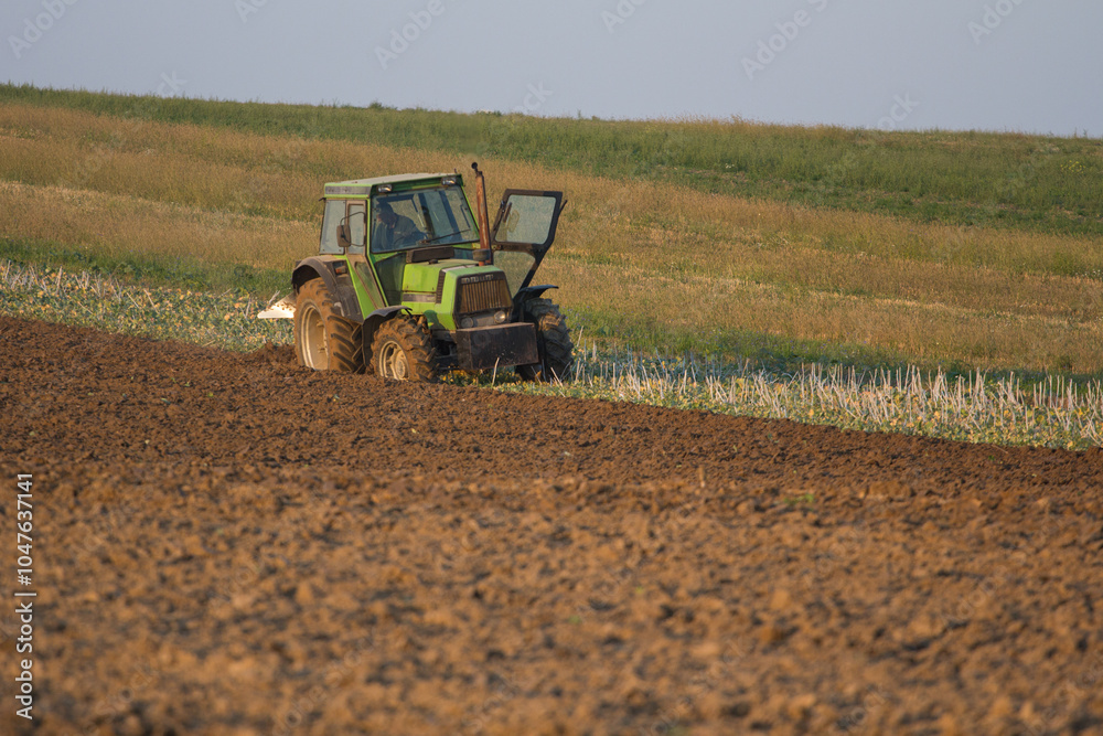 Fototapeta premium Agriculture machinery in action a tractor plows a field on a bright day