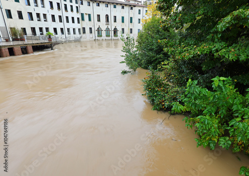 muddy river bend that has already flooded the public park and is now lapping at the city houses