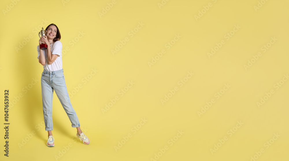 Happy winner with gold trophy cup on yellow background Happy winner with gold trophy cup on yellow background