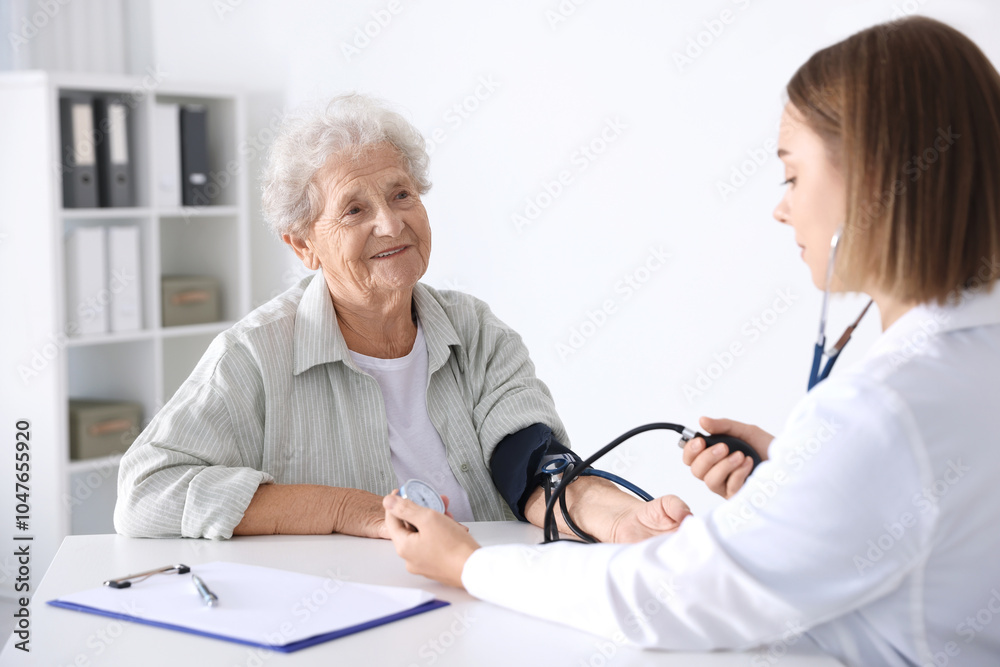 Doctor measuring patient's blood pressure at table in hospital Doctor measuring patient's blood pressure at table in hospital