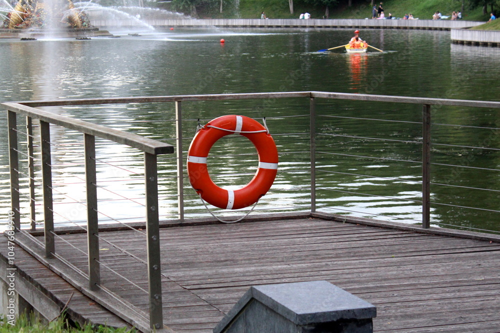 Naklejka premium There is a lifebuoy hanging on the fence at the pier near the reservoir. 