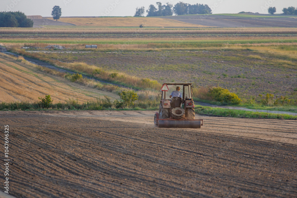 Obraz premium Ploughing a field at sunset with a tractor and plough, ready for crops on a farm