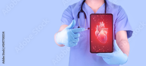 Doctor analyzes heart via his tablet. Concept of modern technology for heart disease treatment. Cardiologist isolated on light blue background. photo