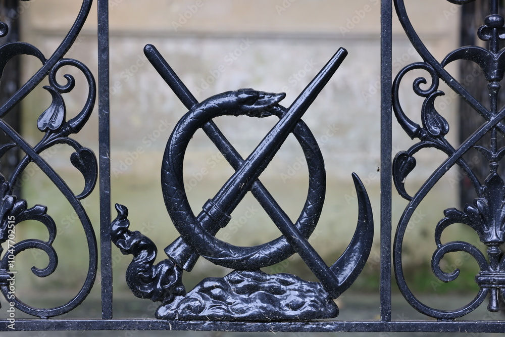 decorative metal fence with scythe, Ouroboros and extinguished torch close up