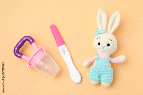 Pregnancy test, nibbler and toy bunny on pale orange background, top view photo