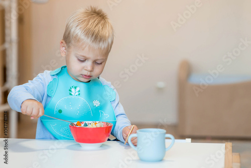 Baby food. Eating. Feeding the baby. A cute kid eats on his own with a spoon. Healthy eating. Family and children.