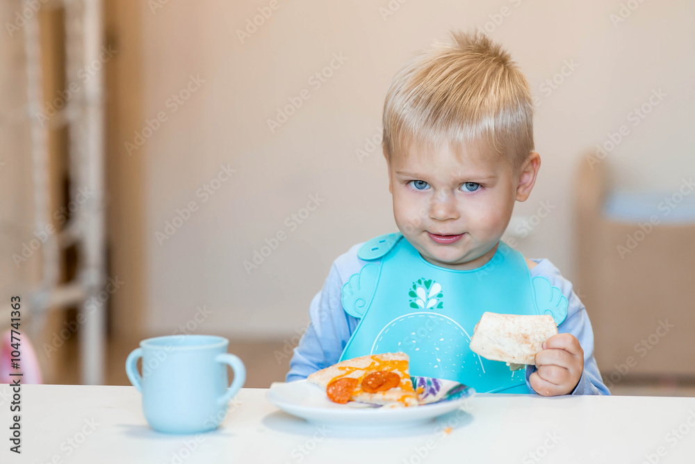 Unhealthy food for children. Eating. A cute 2-year-old kid eats pizza for lunch. Fast food. Family and children. Unhealthy food for children. Eating. A cute 2-year-old kid eats pizza for lunch. Fast food. Family and children.
