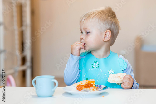 Unhealthy food for children. Eating. A cute 2-year-old kid eats pizza for lunch. Fast food. Family and children.