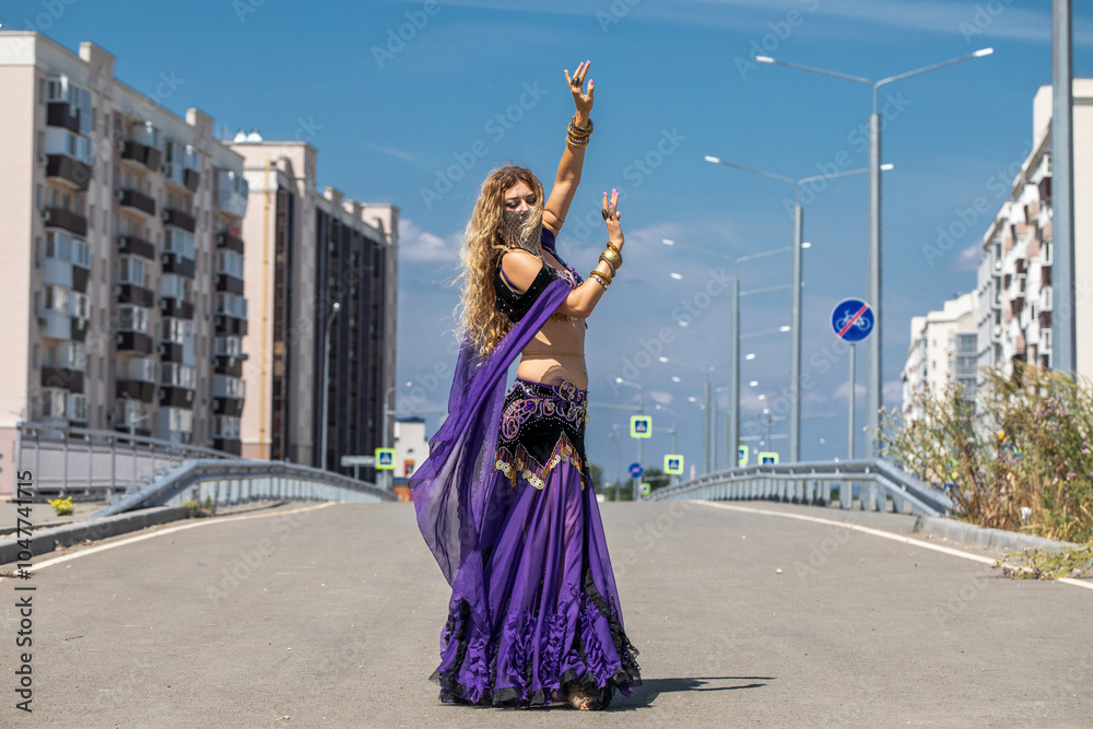 Naklejka premium Sexy beautiful woman in a purple costume dances on the street