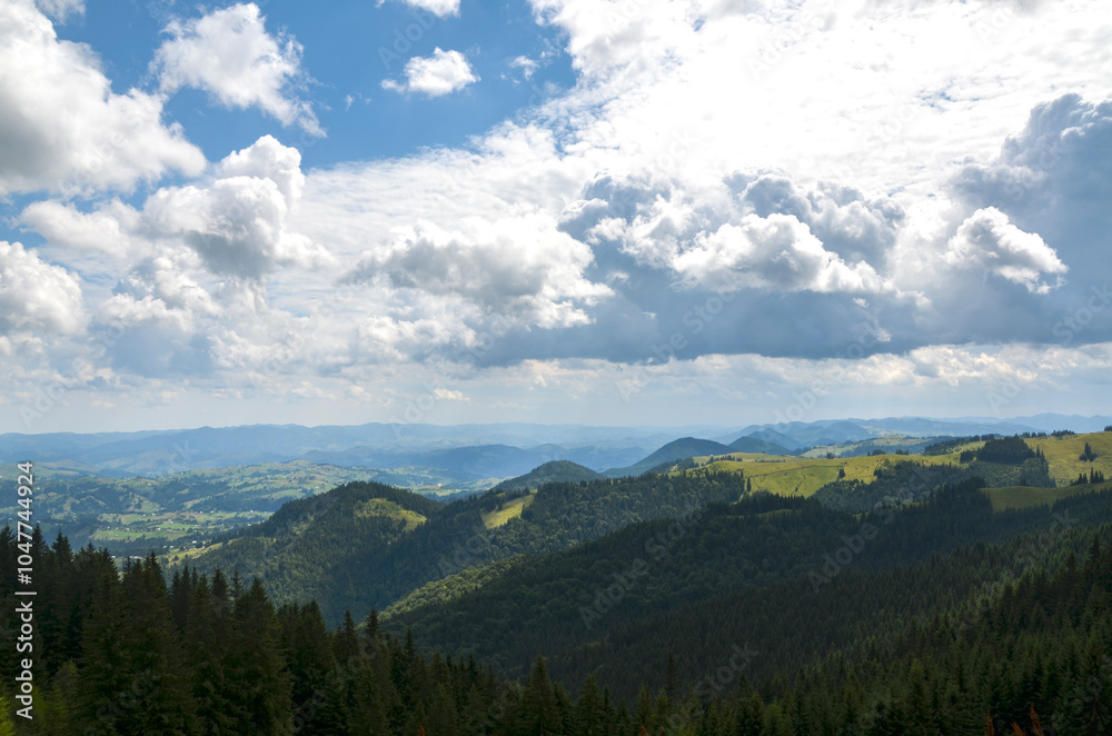 Scenic summer landscape of mountains covered with dense forests and green valleys and hills bathed in sunlight under a cloudy sky. Carpathian Mountains, Ukraine Scenic summer landscape of mountains covered with dense forests and green valleys and hills bathed in sunlight under a cloudy sky. Carpathian Mountains, Ukraine