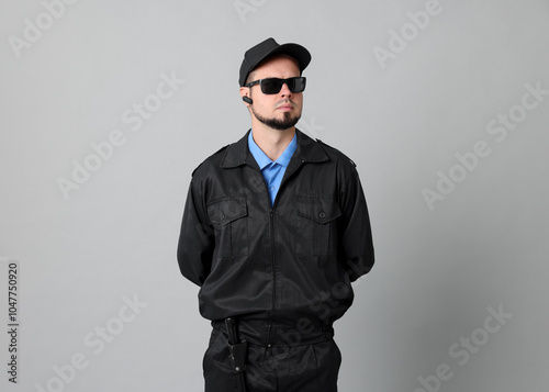 Security guard in uniform and sunglasses on grey background