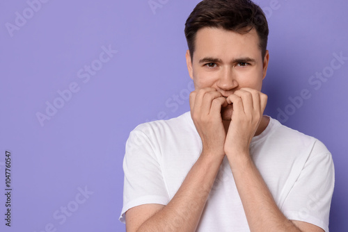 Portrait of scared young man on violet background, space for text