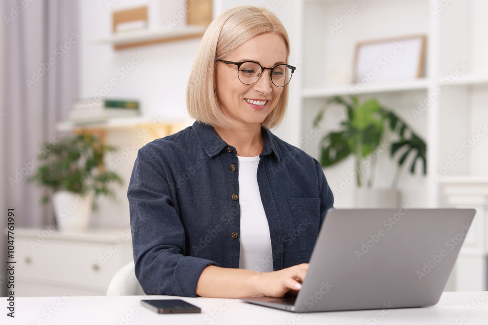 Portrait of smiling middle aged woman with laptop at table indoors Portrait of smiling middle aged woman with laptop at table indoors