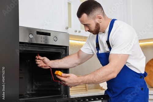 Repairman testing oven element with multimeter in kitchen