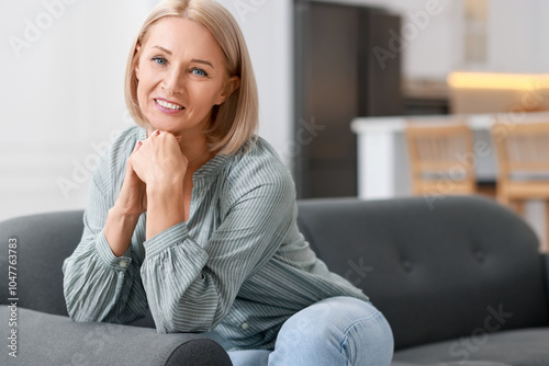 Happy middle aged woman on sofa indoors, space for text