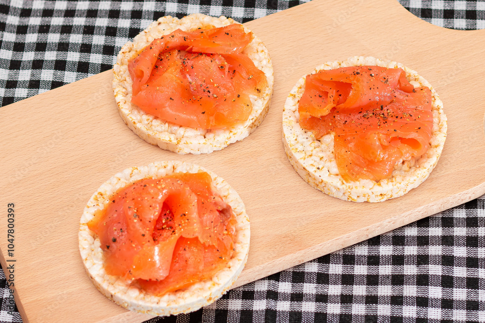 Tasty Rice Cake Sandwiches with Fresh Salmon Slices on Cutting Board - Top View. Easy Breakfast and Diet Food. Crispbread with Red Fish. Healthy Dietary Snack Tasty Rice Cake Sandwiches with Fresh Salmon Slices on Cutting Board - Top View. Easy Breakfast and Diet Food. Crispbread with Red Fish. Healthy Dietary Snack