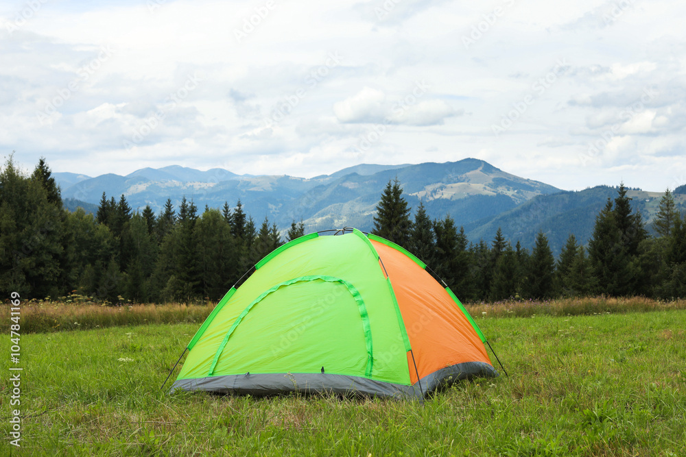 Tent on green grass in mountains. Camping equipment