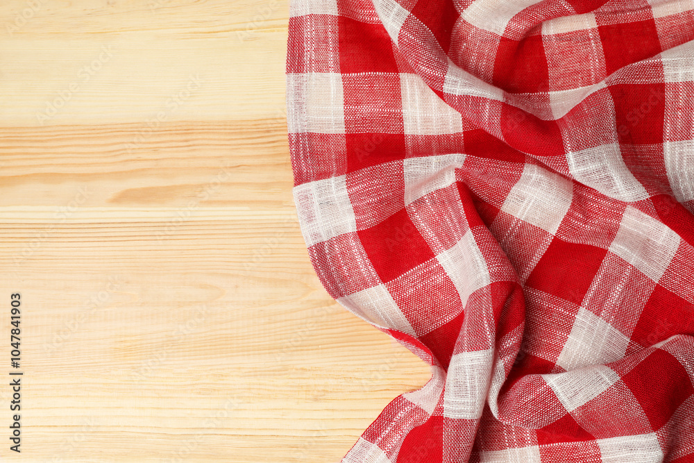 Obraz premium Crumpled tablecloth with checkered pattern on light wooden table, top view. Space for text