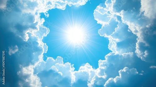 Fototapeta Naklejka Na Ścianę i Meble -  Bright sun shining through a hole in white clouds against a bright blue sky.