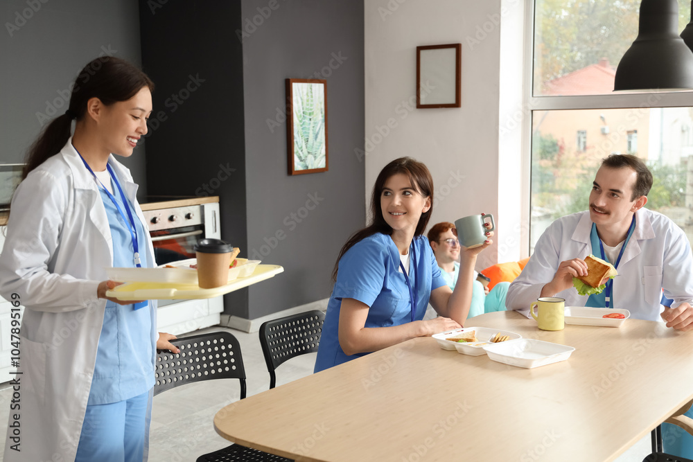 Team of young doctors having lunch at table in hospital kitchen Team of young doctors having lunch at table in hospital kitchen