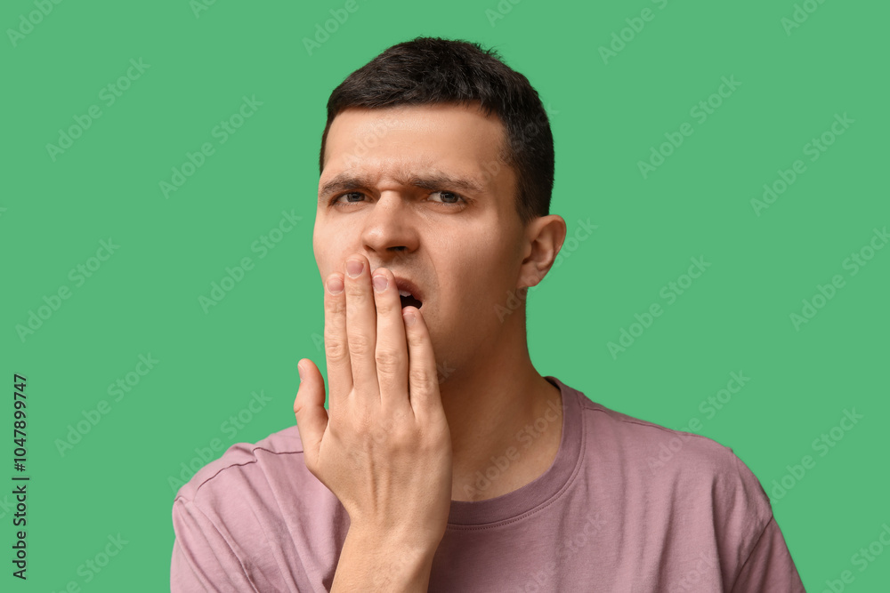 Handsome young man feeling bad smell from mouth on green background Handsome young man feeling bad smell from mouth on green background