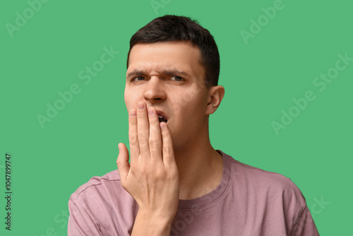 Handsome young man feeling bad smell from mouth on green background