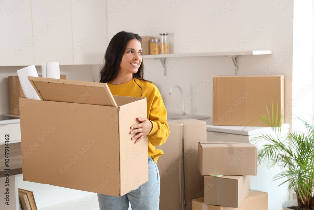 Beautiful woman carrying box in kitchen on moving day Beautiful woman carrying box in kitchen on moving day