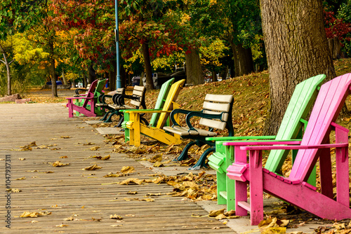 colorful beach chairs and benches on a wooden boardwalk in fall with a background of trees and fallen leaves shot at Balmy Beach in Toronto's Beaches neighbourhood