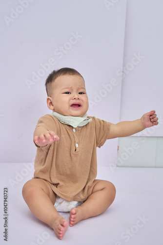 A Baby Sitting on the Floor with His Arms Out, the baby wants to hold up, his face grimaced