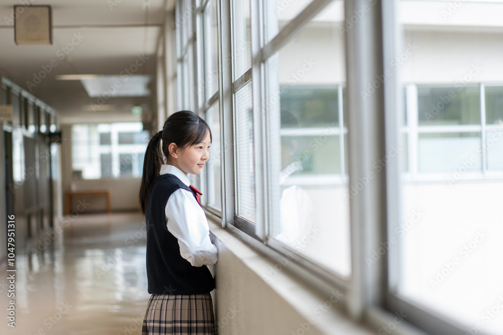 Fototapeta premium 校舎の廊下の窓の外を見ている日本人の女子中学生のポートレート